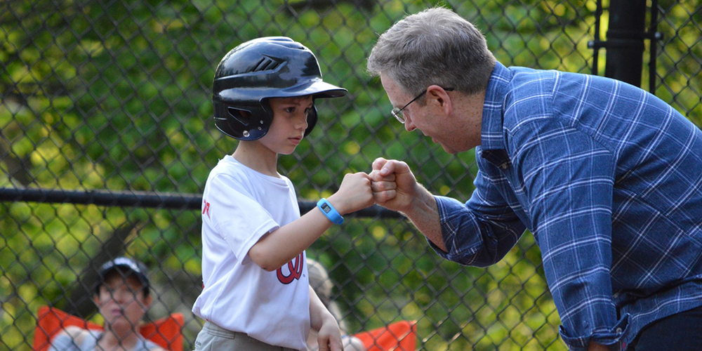 Volunteer Fist Bumping a Little Leaguer